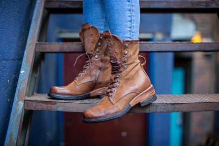 A woman stands on some stairs wearing brown high top boots from Shoes for the Soul