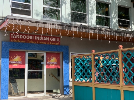 the tandoori grill building with lights hanging down and a green patio fence
