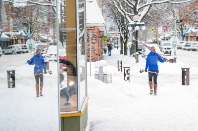 Woman walking downtown Nelson BC carrying cross country skis