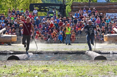 Two men running on a log in water during Kaslo Logger Sports at May Days in Kaslo, BC.