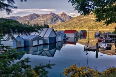 The boat houses in Kaslo BC with a very clear reflection in water and mountains in the background