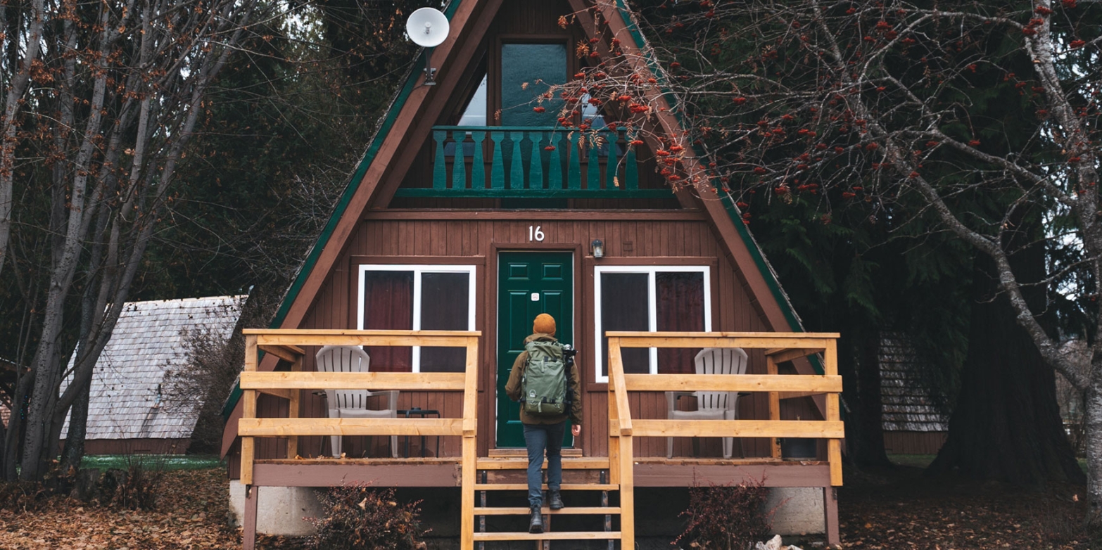Person walking up the front steps to a cozy cabin.