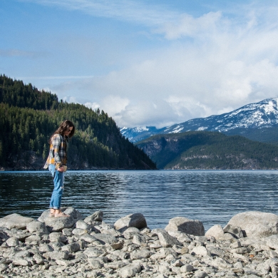 A girl standing on a rock on the beach in Kaslo, BC