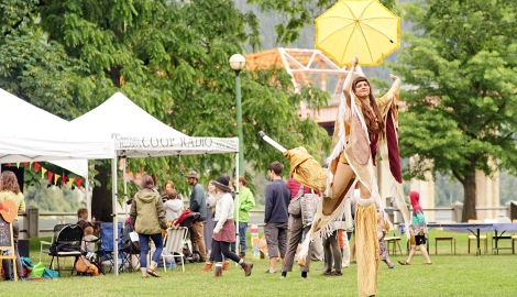 A lady walking on stilts in costume in the park for an AFKO gathering