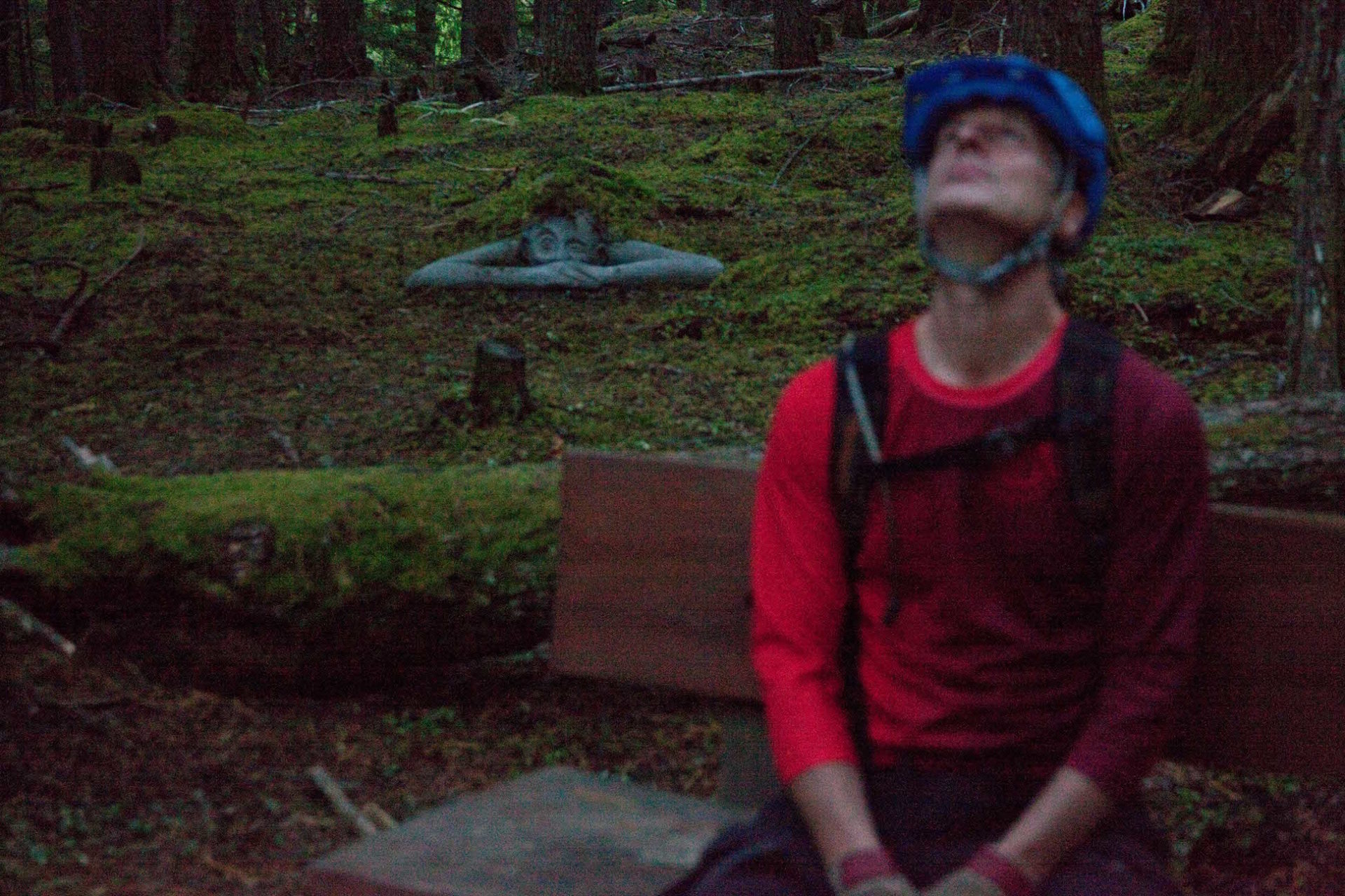 One of the Koots statues peaks out from under the moss along the River Trail in Kaslo. Photo by Peter Moynes.