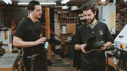 Seven of the staff at DeVito's shoes smiling, each holding a shoe,