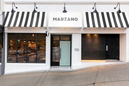 The outside of the Marzano restaurant showcasing white and black awnings