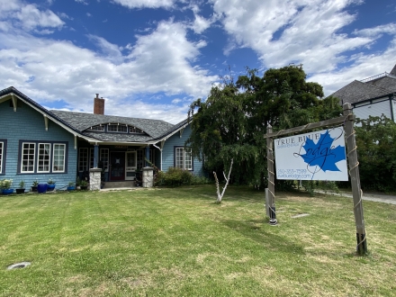 The True Blue Lodge sits in Kaslo, BC with a green yard and tall sign