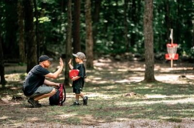 child and man high fiving after playing disc golf