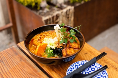 Bowl of Butternut Miso Tofu Ramen on a Patio Table With Chopsticks.