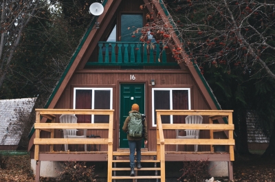 Person walking up the front steps to a cozy cabin.