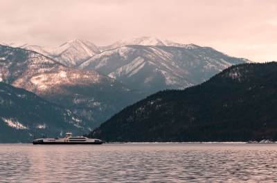 Kootenay Lake Ferry on the water with snowcapped mountains in background.