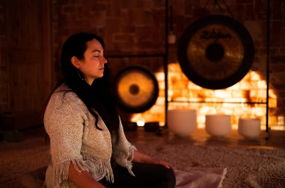A woman meditates in the pink Himalayan Salt Cave, with gongs and sound bowls in the background,in Nelson. Photo by Wies van Wetten