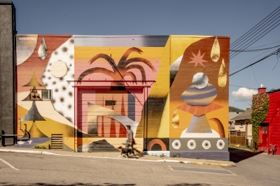 A person walking their dog in front of a beautiful mural in Nelson BC.
