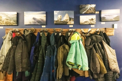 A rack of winter jackets below some canvas prints of snowy mountains in Nelson BC