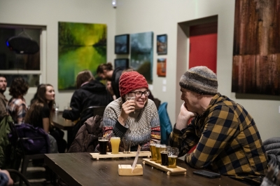 A couple on a date drinking beer and staring lovingly into each others eyes.