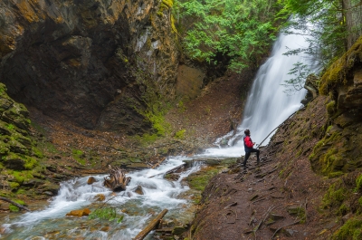 A person standing in front of Fletcher Falls in Kaslo, BC. 