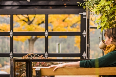 Girl sitting inside of a cafe atrium sipping a coffee and looking at the fall colours.