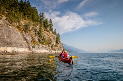 Two people on a double kayak paddling on Kootenay Lake near Kaslo, BC