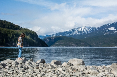 A girl standing on a rock on the beach in Kaslo, BC