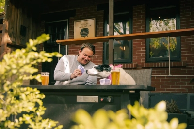 A man and dog playing cards and drinking beer on the patio of the Black Cauldron in Nelson BC.