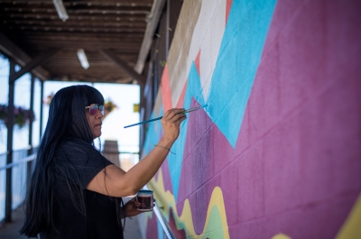 An artist painting a colourful mural at Ainsworth Hot Springs Resort - Nelson BC Heritage Buildings