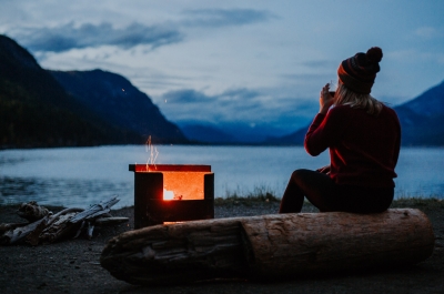A girl sitting by a campfire on the shores of Kootenay Lake, BC.