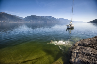 Jumping into Kootenay Lake with a sailboat in the background. 