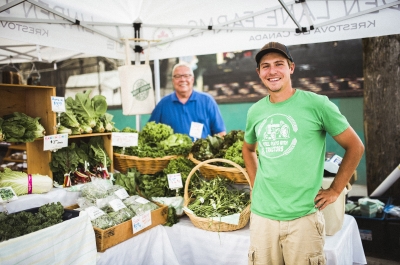 A farmer stands with a table full of produce at the Nelson Downtown Market