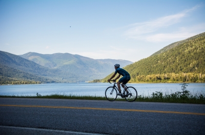 A road cyclist pedalling along the shores of Kootenay Lake.