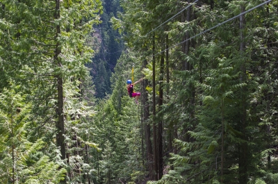 young girl in pink zip-lining through the forest in Kokanee Provincial Park