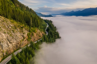 Winding highway between a foggy lake and mountains