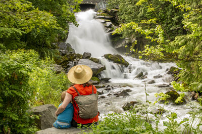 A mother and son sitting in front of Cottonwood Falls in Nelson BC.
