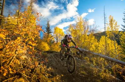 A person riding down a steep mountain bike trail surrounded by vibrant fall colours.