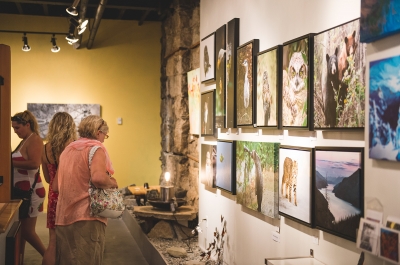 Several people looking at art hung on the walls of Craft Connection Gallery during Nelson, BC Artwalk