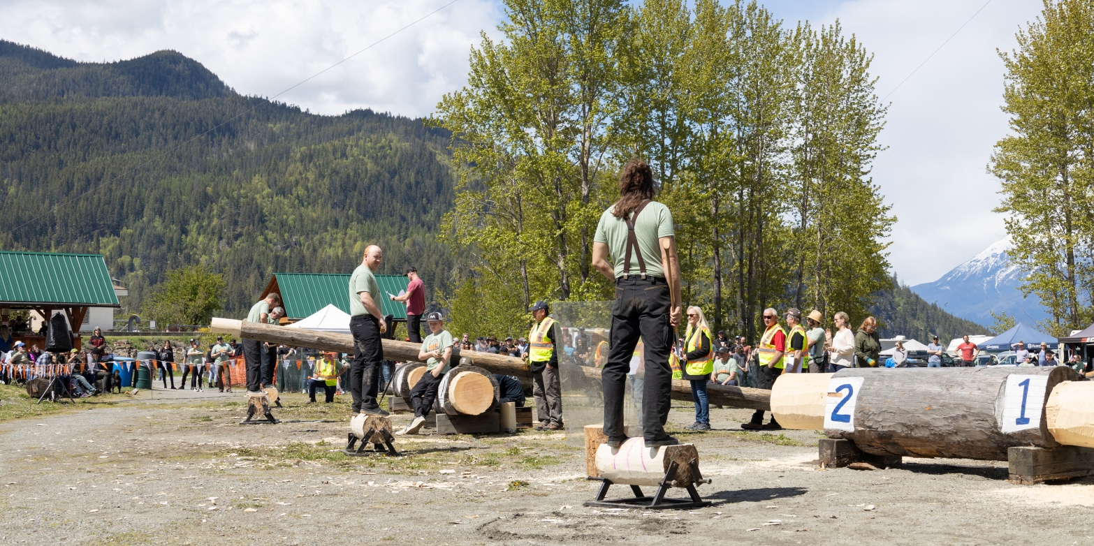 People standing on logs with axes preparing to participate in the Kaslo Logger Sports