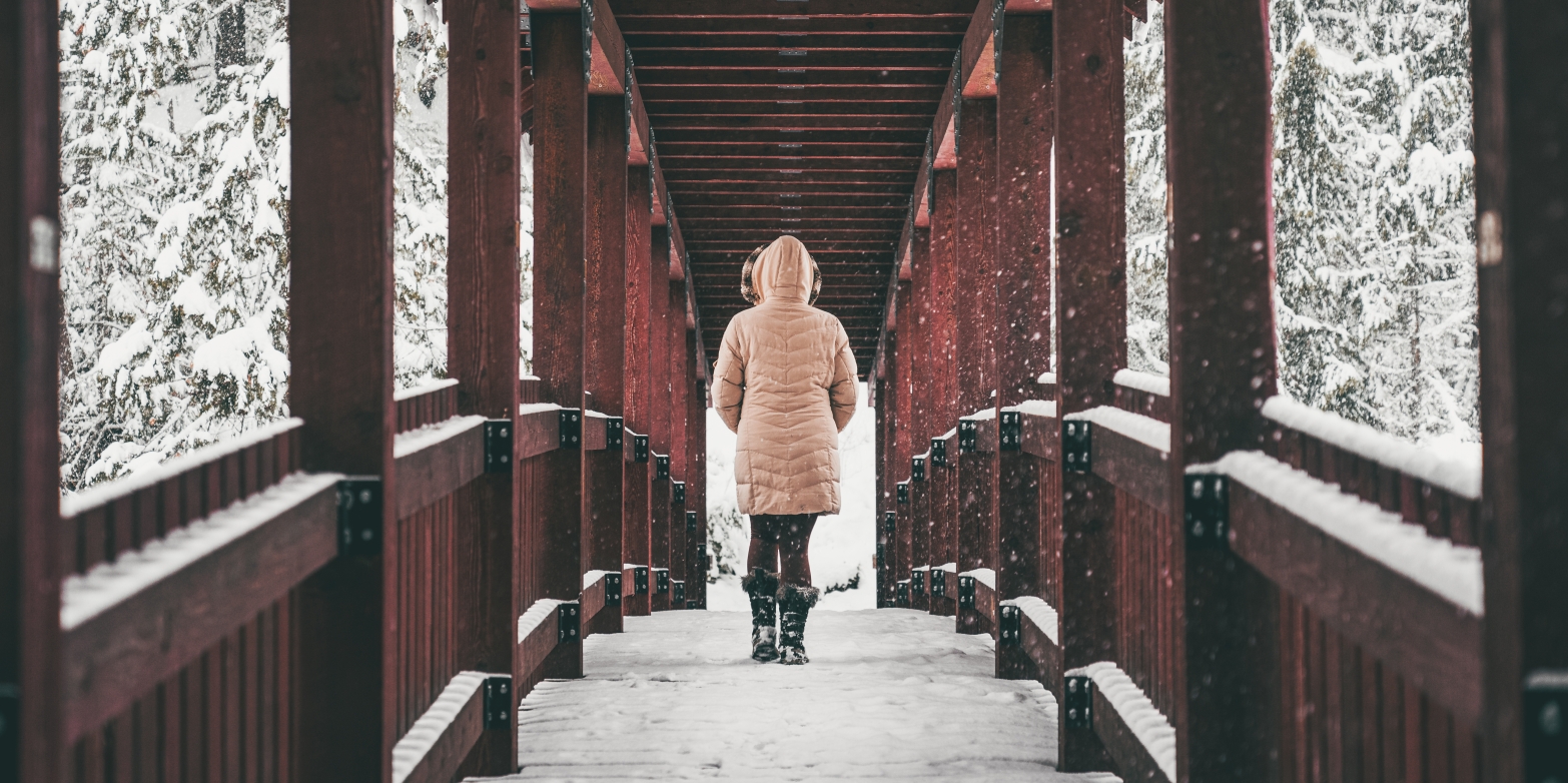 Person walking across one of the red bridges on the Kaslo River Trail