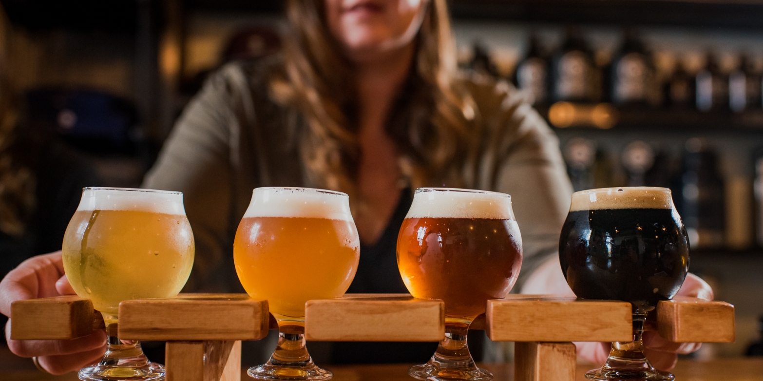 A bartender offers a flight of beer.