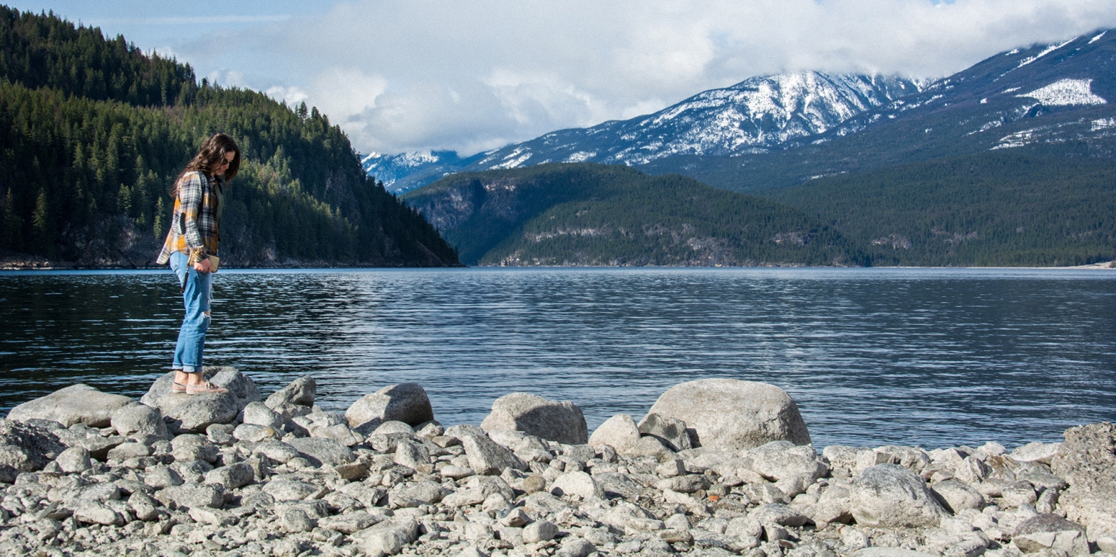 A girl standing on a rock on the beach in Kaslo, BC