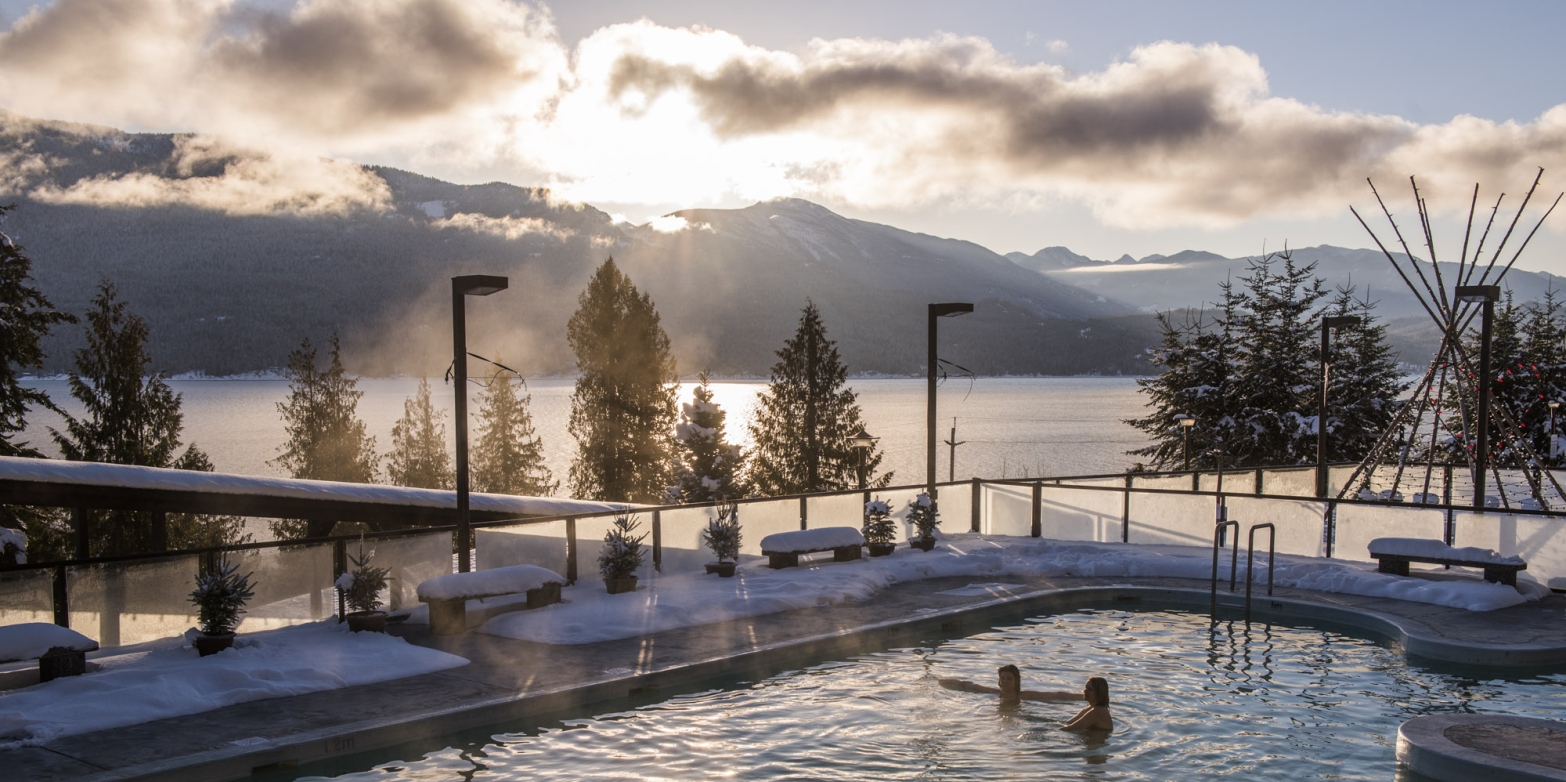 Two people in the main pool at Ainsworth Hot Springs Resort on a sunny winter day.
