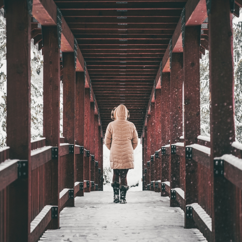 Jesse Schpakowski | Kaslo River Trail Person walking across one of the red bridges on the Kaslo River Trail