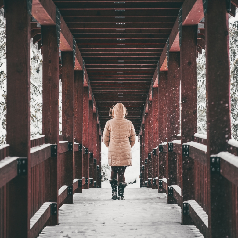 Person walking across one of the red bridges on the Kaslo River Trail