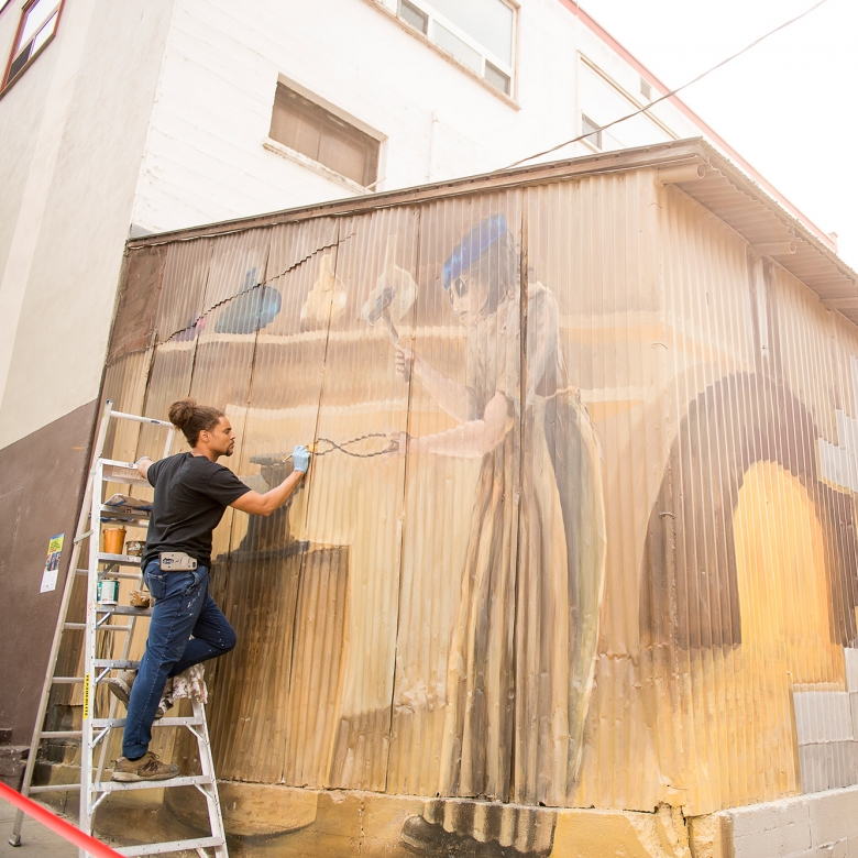 Two artists painting a mural during the Nelson International Mural Festival