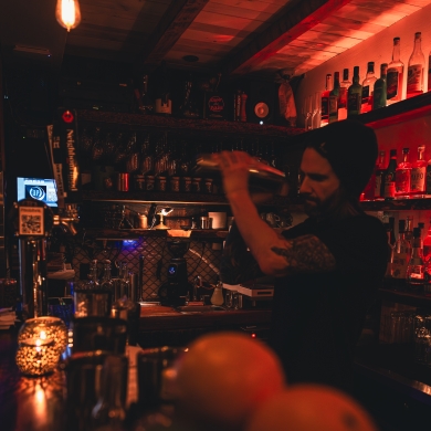 A Bartender shaking a cocktail in a dim lit bar