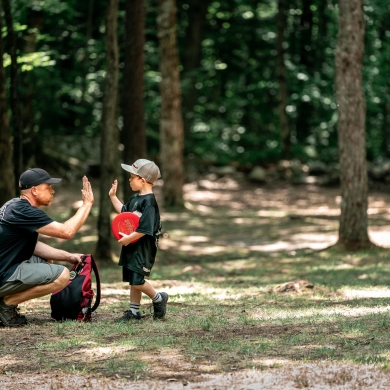 child and man high fiving after playing disc golf
