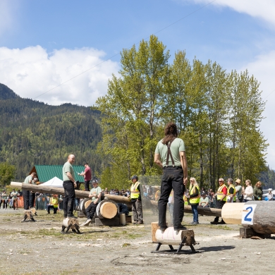 People standing on logs with axes preparing to participate in the Kaslo Logger Sports