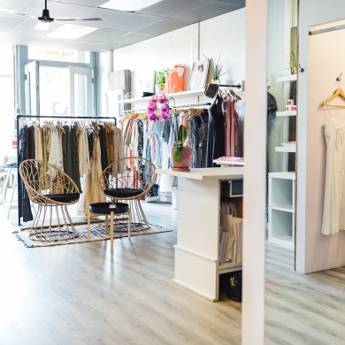 Clothing racks and wickers chairs in the bright daylight at Scout Clothing. 