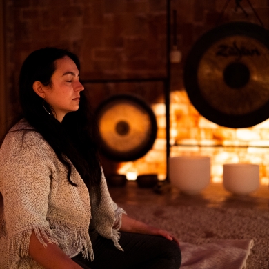 A woman meditates in the pink Himalayan Salt Cave, with gongs and sound bowls in the background,in Nelson. Photo by Wies van Wetten