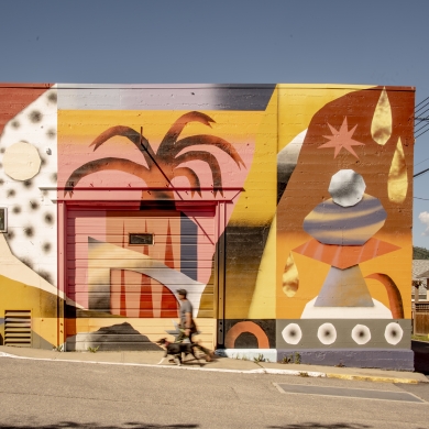 A person walking their dog in front of a beautiful mural in Nelson BC.