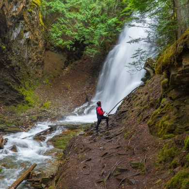 A person standing in front of Fletcher Falls in Kaslo, BC. 